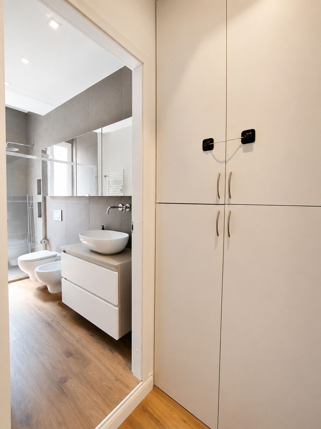 A modern bathroom with a large mirror, a white sink, and a shower area.