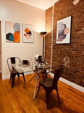 A dining area with a glass table, black chairs, and abstract art on the walls. - Real Cozy Apartment in Downtown Manhattan (New York)