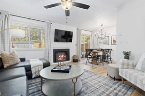 A modern living room with a fireplace, a dining area, and a ceiling fan. - Private Hot Tub + Sauna · Lakeside · Dog-Friendly · Trails (Frisco)
