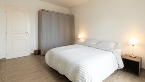 Een slaapkamer met een bed, twee bedlampen, een kledingkast en een deur.