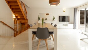 Een moderne eetruimte met een houten trap, een grote eettafel en stoelen.