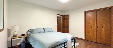 Une chambre à coucher comprenant un lit, une table de chevet, une lampe, une horloge et une armoire.