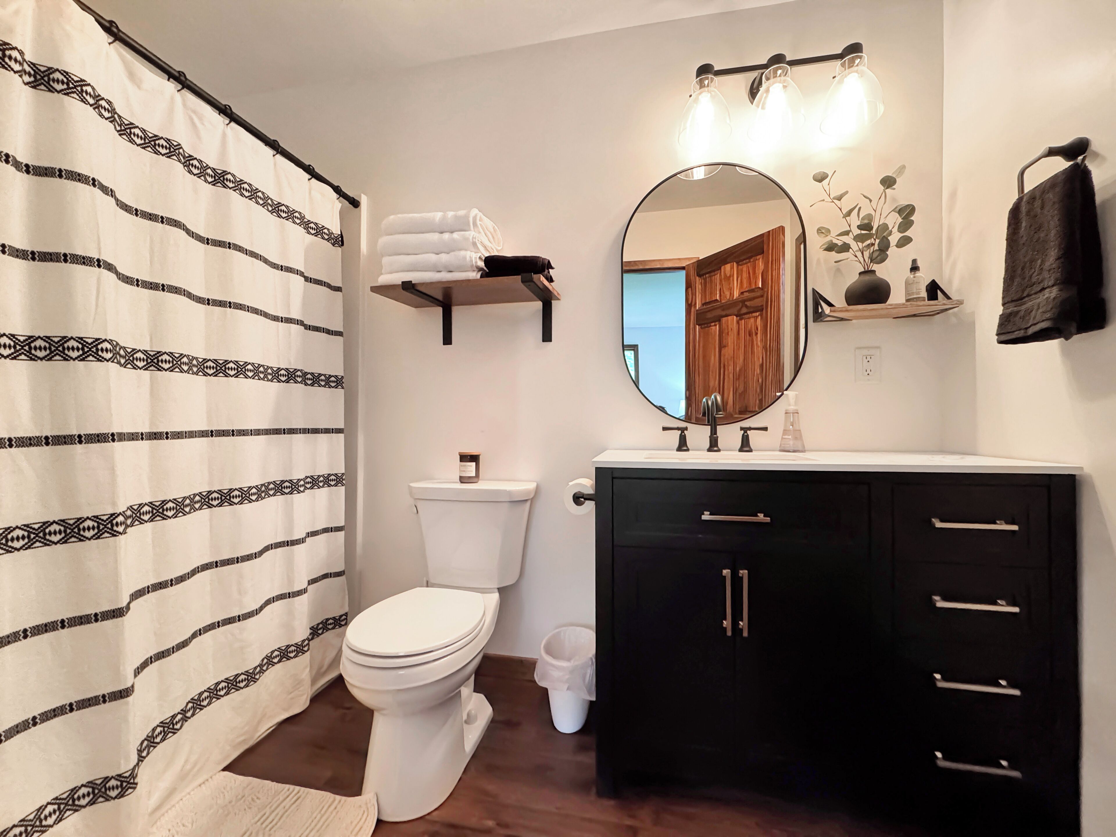 A bathroom with a toilet, a sink with a mirror, a towel rack, and a shower curtain.