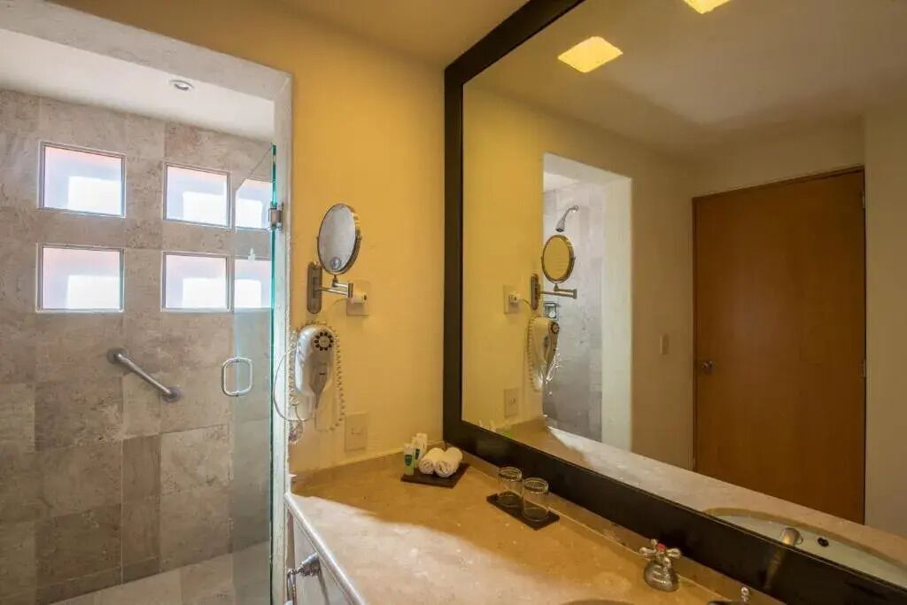 Un baño moderno con cabina de ducha de vidrio, un espejo grande y tocador con lavabo y perchero para toallas.