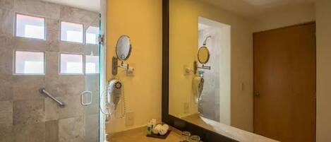 Un baño moderno con cabina de ducha de vidrio, un espejo grande y tocador con lavabo y perchero para toallas.