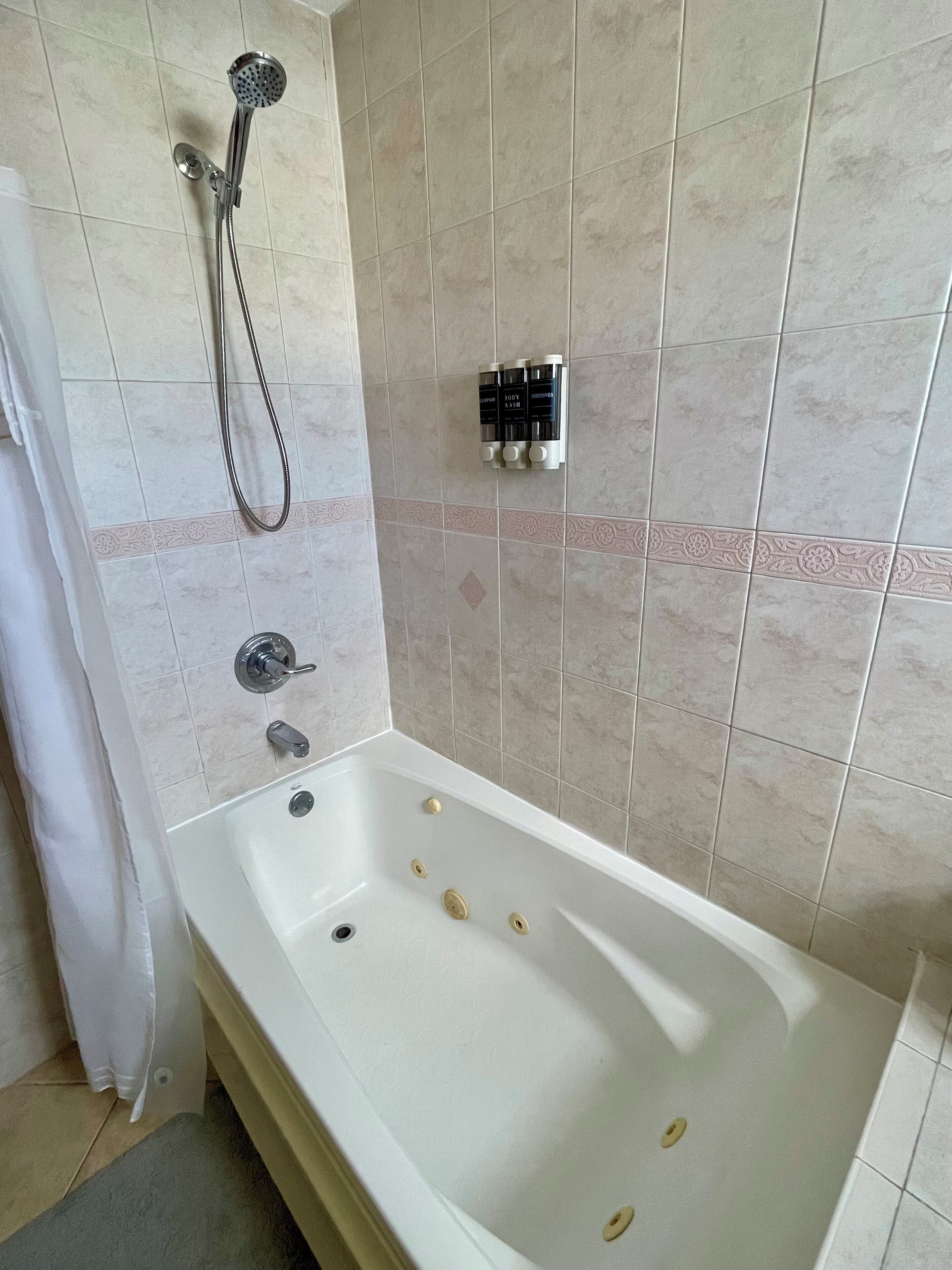 A bathroom with a bathtub, a showerhead, and a towel rack.
