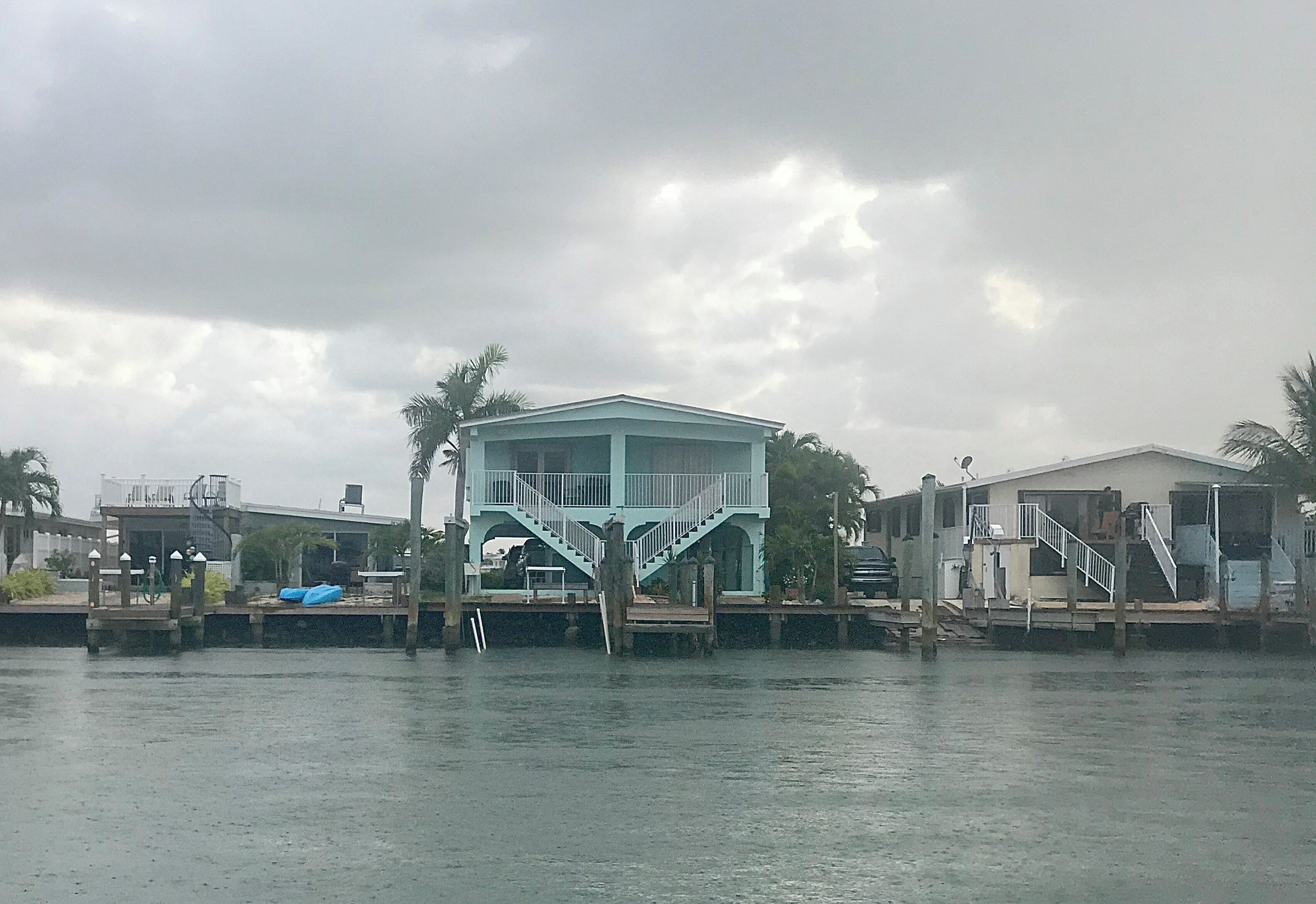 Propiedad frente al agua con un edificio central, un muelle y construcciones adyacentes.