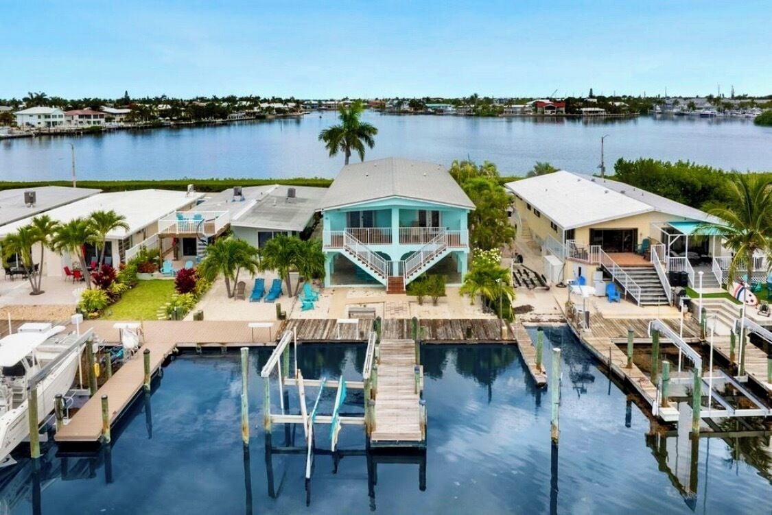 A waterfront property with a central building, docked boats, and a swimming pool.