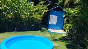 A blue inflatable pool surrounded by lush greenery and a small blue shed with a sign. - luna caribena (Cahuita)