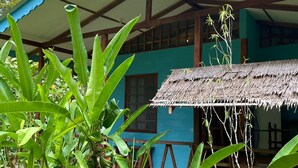 A traditional house with a thatched roof, a blue exterior, and a wooden structure with a white roof. - luna caribena (Cahuita)