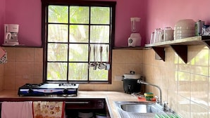 A kitchen with a gas stove, sink, window, and various kitchen utensils. - luna caribena (Cahuita)