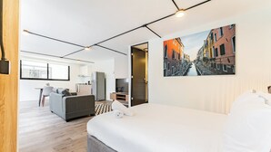 A modern hotel room with a large bed, a sofa, a desk, and a view of a canal through a window. - VH | Loft Condesa with great concierge service | 253 (Ciudad de México)