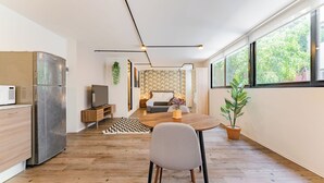 A modern kitchen with a built-in refrigerator, a dining area with a wooden table and chairs, and a living area with a sofa and a TV. - VH | Loft Condesa with great concierge service | 253 (Ciudad de México)