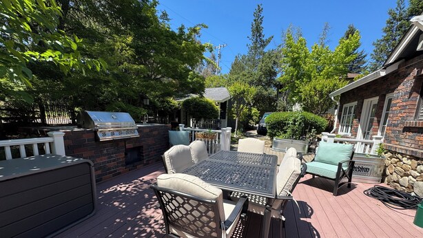 An outdoor patio with a grill, seating area, and a stone wall.