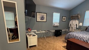 Une chambre à coucher avec un lit, un bureau, une chaise, un téléviseur et une fenêtre.