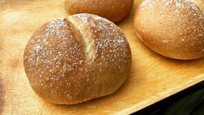 Drei runde Brötchen auf einer Holzteller.