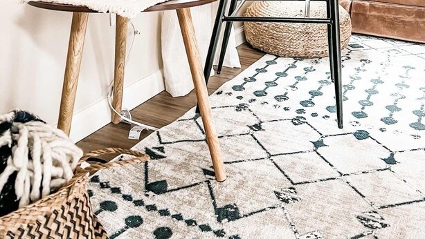 A cozy living room with a wicker chair, a small side table, a potted plant, and a patterned rug. - Hideaway Cabin. Relax and Enjoy (Manistee)