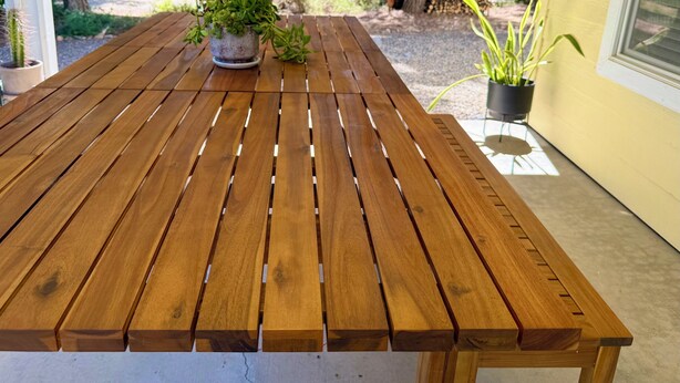 Une table de patio en bois, agrémentée de plantes en pot.