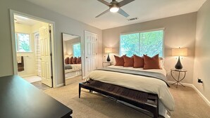 Une chambre à coucher avec un lit, des lampes de chevet, un ventilateur de plafond et une grande fenêtre.