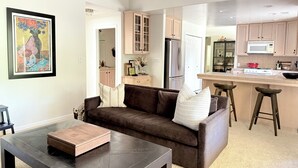 Un salon moderne avec un canapé marron, une table basse et une œuvre d’art encadrée accrochée au mur.