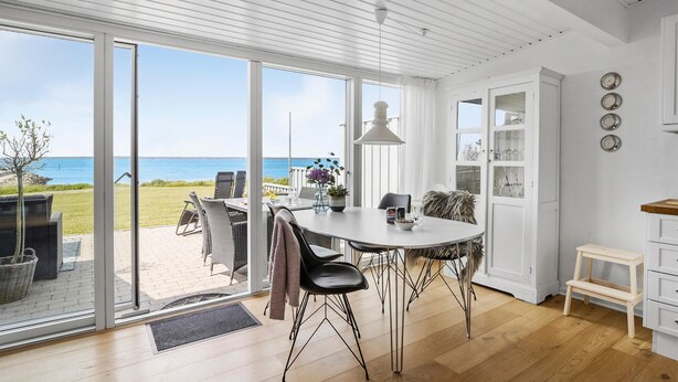 A modern kitchen with a large island, a dining area with a view of the sea, and a cozy seating area with a view of the beach. - Awesome home in Tranekær with WiFi (Tranekær)