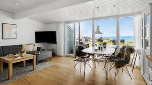 A modern living room with a grey sofa, a wooden coffee table, a flat-screen TV, and a dining area with a round table and chairs. - Awesome home in Tranekær with WiFi (Tranekær)