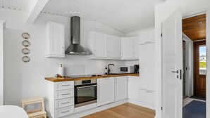 A modern kitchen with white cabinetry, a wooden countertop, a stainless steel range hood, and a built-in oven. - Awesome home in Tranekær with WiFi (Tranekær)