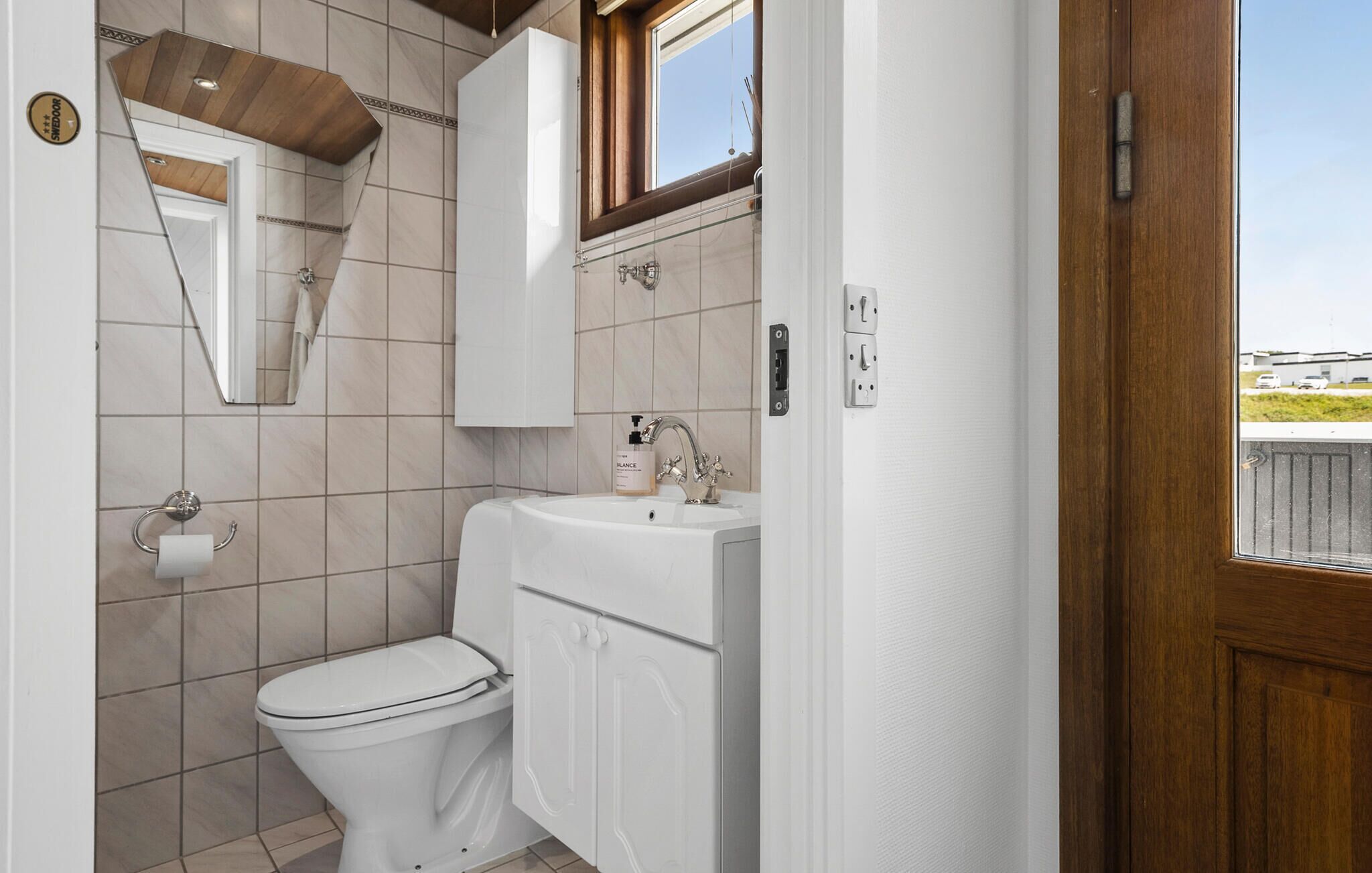 A compact bathroom with a toilet, sink, and mirror.