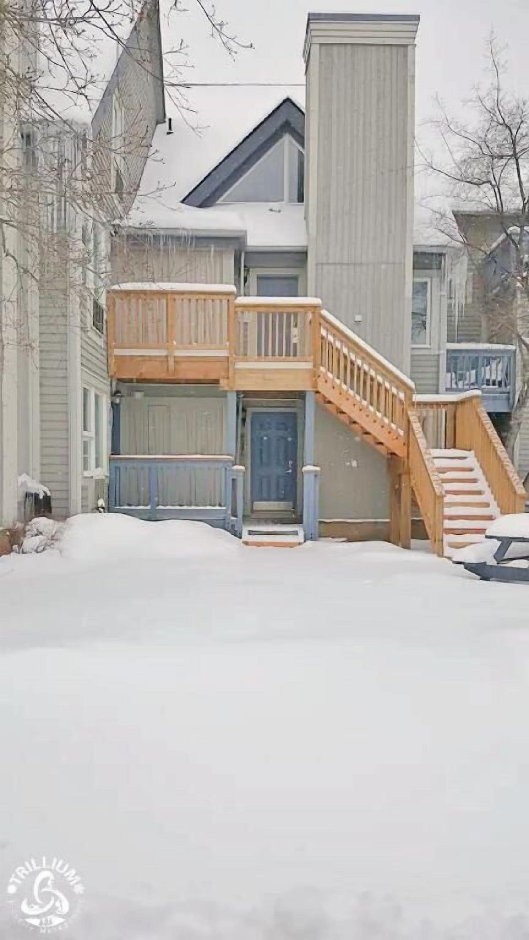 A two-story house with a front porch and a wooden staircase leading to the entrance.
