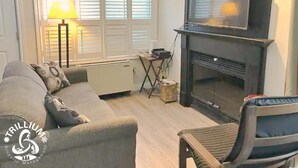 Un salon avec un canapé, un téléviseur, une cheminée et une lampe.
