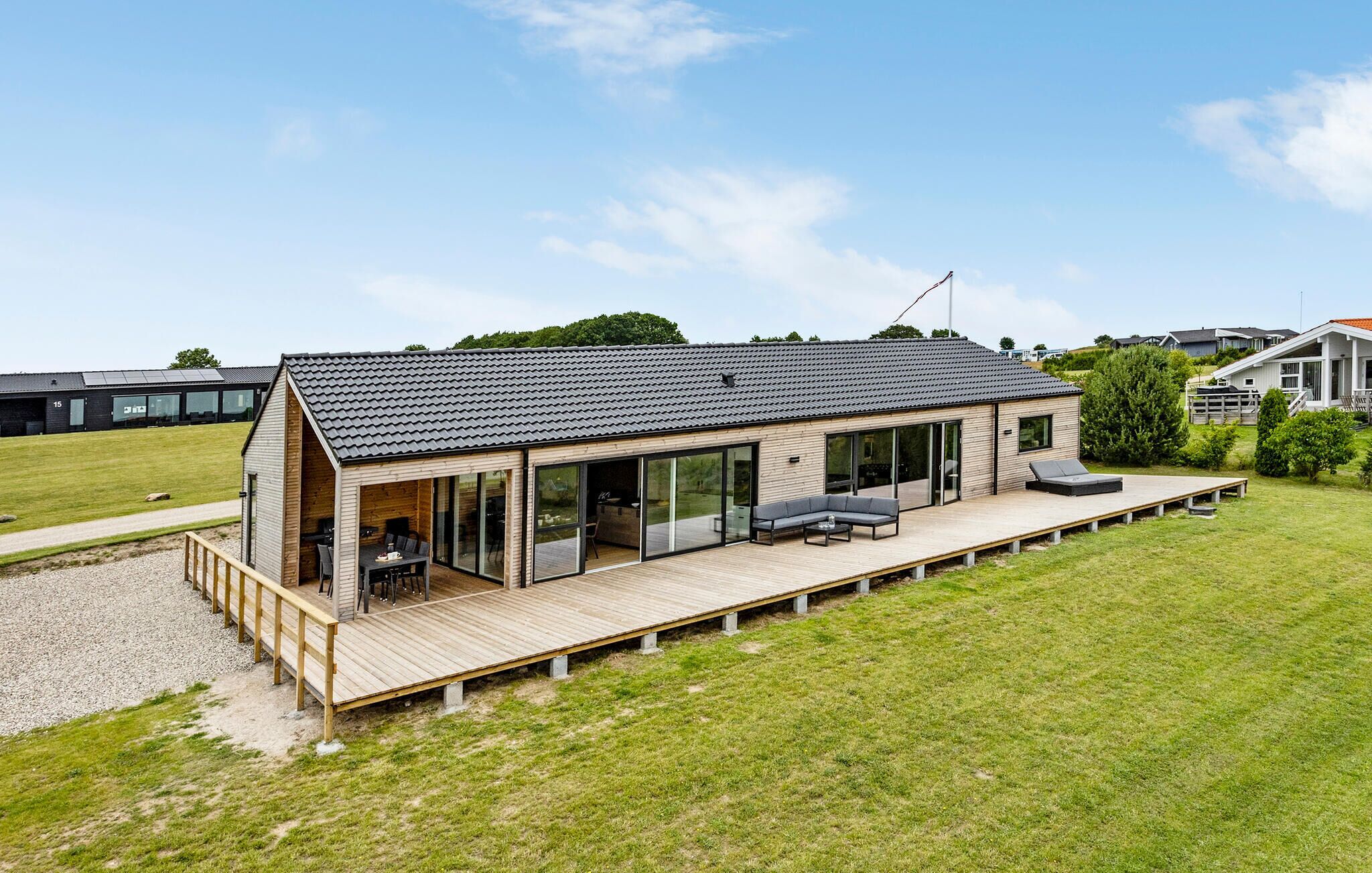 A modern house with a large deck, sliding glass doors, and a sloped roof.