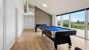 Ett modernt biljardbord för inomhusbruk med utsikt över omgivningen genom stora fönster.