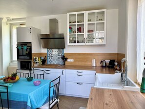 Una cocina moderna con armarios blancos, horno empotrado y encimera de madera.