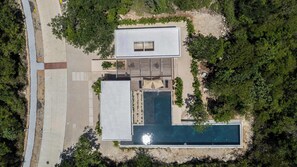 Vue aérienne d’un bâtiment moderne doté d’une piscine, entouré de verdure.