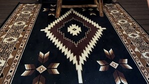 Une pièce aménagée avec une tente, un lit, un petit banc en bois et un tapis à motifs.