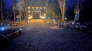 Une arche rustique en bois, surmontée d’une pancarte « Bienvenue », entourée de rochers et d’arbres.