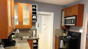 A kitchen with wooden cabinets, a stainless steel sink, a microwave, and a stove. - Charming 1-bedroom apartment with WiFi, AC in marvelous Cincinnati (Cincinnati)