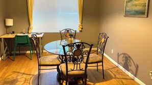 A dining area with a round table, four chairs, a lamp, and a window with curtains. - Charming 1-bedroom apartment with WiFi, AC in marvelous Cincinnati (Cincinnati)