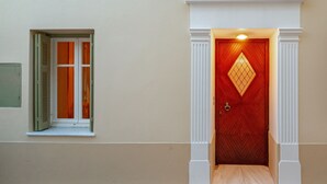 A wooden door with a diamond-shaped window, white trim, and a small step leading up to it. - A charming retreat with timeless beauty (Andros Chora)