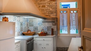A kitchen with a stone ceiling, checkered floor, and a hanging light fixture. - A charming retreat with timeless beauty (Andros Chora)