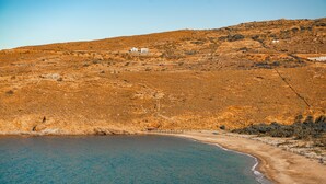 A coastal landscape with a beach and a hillside with buildings. - A charming retreat with timeless beauty (Andros Chora)