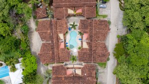 An aerial view of a resort with multiple bungalow-style buildings, a central swimming pool, and lush surrounding greenery. - Ocotal - 2 Full Units - Steps to the Beach (Sardinal)