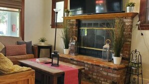 Una sala de estar acogedora con chimenea, un sofá, una mesita de centro y un televisor.