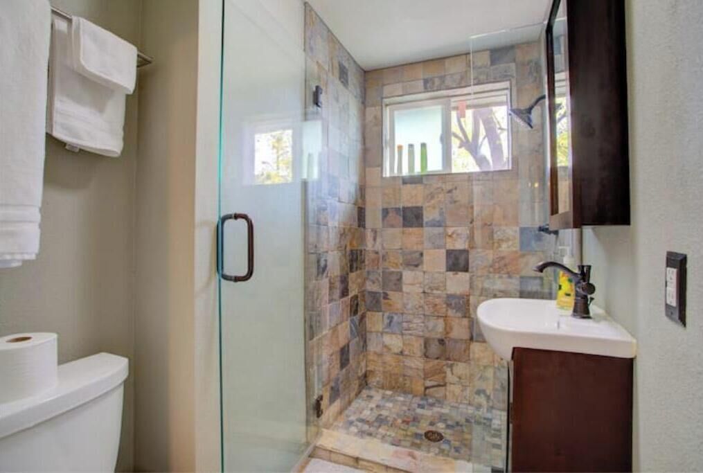 A bathroom with a glass shower enclosure, a white sink, and a mirror.