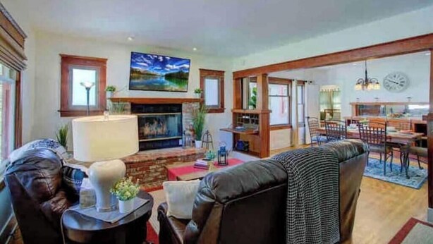 Un salón amplio con chimenea, un comedor con candelabro y un cuadro grande en la pared.