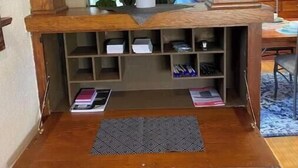 Un estante de madera con un espejo, una planta en maceta y un reloj en la pared.