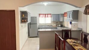 Una cocina amplia con una isla central, una zona de comedor con mesa y sillas, y un refrigerador visible.