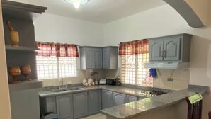 Una cocina con gabinetes grises, una isla central y un ventanal con cortinas.