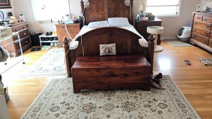 Una camera da letto con un letto in legno, una cassettiera, un comodino e una finestra.