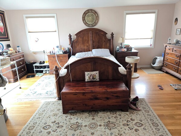 Un dormitorio con una cama de madera, un tocador, una mesita de noche y una ventana.